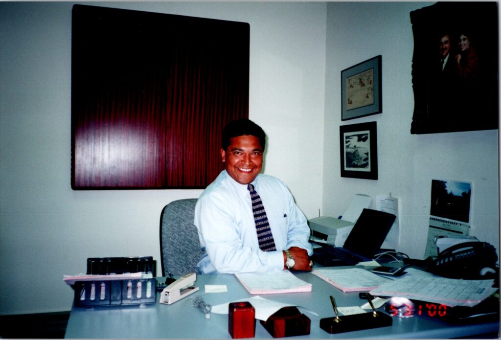 Old photo of ernesto sitting at his office desk smiling at the camera