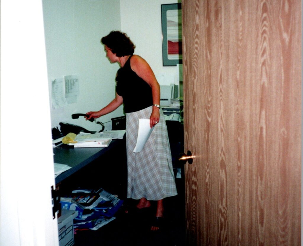 old photo of stacy looking over paperwork inside of an office room