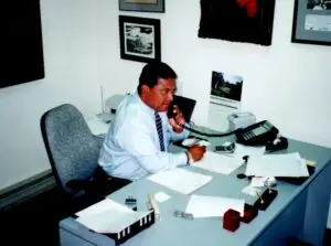 Ernesto Moreno sitting at his desk using a landline phone. This is an old photo taken in the year 2000.