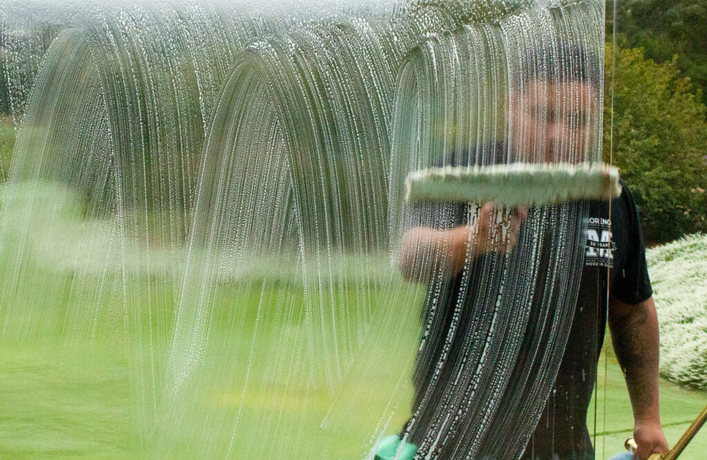 man washing glass window